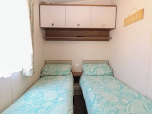 A small room with two beds, a wooden cabinet above, and a sign that says 'BEACH'.