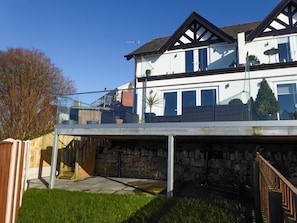 A two-story house with a balcony, stone foundation, and a staircase leading to the upper floor.