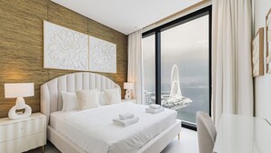 Moderni hotellihuone, jossa on suuri sänky, työpöytä ja näkymä kaupunkimaisemaan.