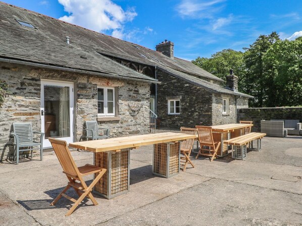 A stone building with outdoor seating, including wooden tables and chairs.