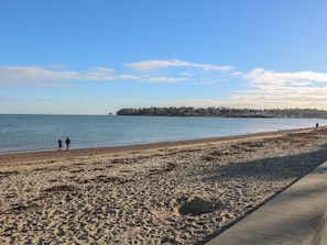 A beach with a concrete walkway, a calm sea, and a distant shoreline with buildings. - 2 Linden Terrace, Brading (Sandown)