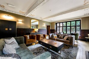 Un salon spacieux doté d’une grande fenêtre, de lambris en bois foncé et d’une cheminée.
