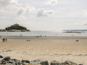 Una platja amb un castell sobre una petita illa al fons.