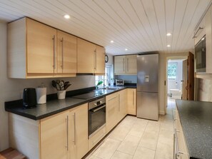 A modern kitchen with light wood cabinets, stainless steel appliances, and a black countertop. - Cherry Cottage, Crowborough (Crowborough)