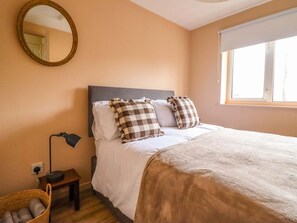 Une chambre à coucher avec un lit, une lampe de chevet, un miroir et une fenêtre.