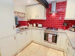 A kitchen with white cabinets, a red tiled backsplash, a gas stove, and a built-in oven. - Rosemount Cottage, Salterforth (Barnoldswick)