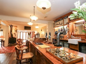 A bar area with wooden bar stools, a tap, and a decorative metal tray. - Poacher's Arms, Hope (Hope Valley)
