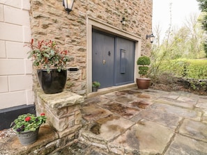 A stone building with a dark blue door, a stone-paved entrance, and potted plants. - Poacher's Arms, Hope (Hope Valley)