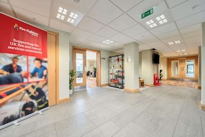 A spacious lobby with a red charity banner, a glass display case, and a fire extinguisher.