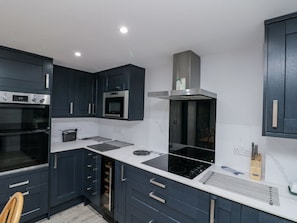 A modern kitchen with dark cabinetry, a built-in oven, a microwave, a stove, and a ventilation hood. - Charming Shelstone Retreat in Whitby (Whitby)
