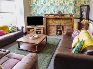 A living room with a fireplace, leather sofas, a coffee table, and a television. - The Yellow House in Withernsea (Withernsea)