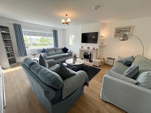 A living room with a sofa set, a fireplace, a television, and a bookshelf. - War Horse Valley Orchard View, Hatherleigh (Winkleigh)
