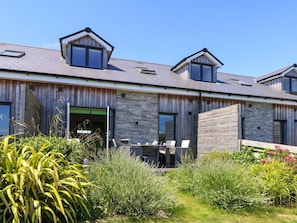 A modern building with a wooden exterior, a stone facade, and a patio with outdoor furniture. - Overcombe Mill, near Weymouth. (Weymouth)