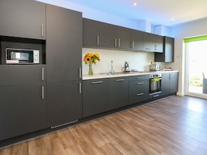 Una cocina moderna con armarios oscuros, un microondas, un fregadero y una estufa.