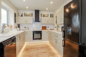 Eine moderne Küche mit weißen Schränken, einem schwarzen Kühlschrank und einem eingebauten Backofen.