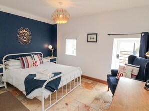A bedroom with a bed, bedside tables, a desk, a chair, a window, and a wall-mounted light fixture. - Valley View, Staithes (Saltburn-by-the-Sea)