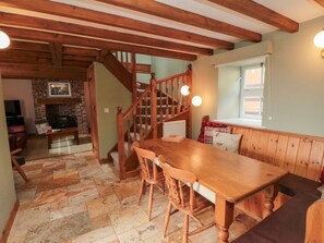 A wooden dining table with chairs, a staircase, and a fireplace in the background. - Valley View, Staithes (Saltburn-by-the-Sea)