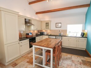 A kitchen with white cabinets, a wooden table, and a large window. - Valley View, Staithes (Saltburn-by-the-Sea)