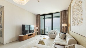 A modern living room with a flat-screen TV, a sofa, a coffee table, and a large window with a view of a Ferris wheel. - Live the Vibe Upgraded 2BR JBR Coastal Living (Dubai)