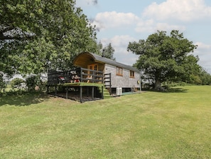 A single-story cabin with a porch, surrounded by trees.