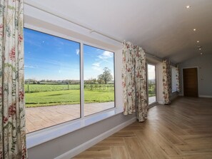 A spacious room with large windows, a herringbone floor, and a view of a green landscape. - Garden Cottage, Cockshutt (Ellesmere)