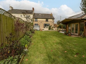 Ein Haus mit gepflegtem Rasen, einem Holzzaun und einem Gartenbereich mit verschiedenen Pflanzen.