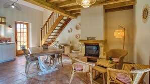 Un vaste espace de vie agrémenté d’un escalier en bois, d’une cheminée, de meubles en osier et d’un téléviseur.