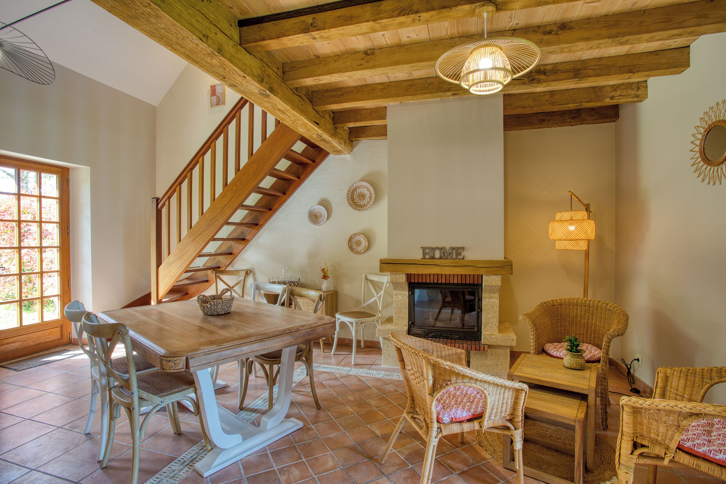 A dining area with a wooden table and chairs, a fireplace, and a staircase.