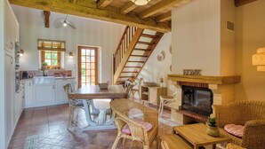 Un vaste espace de vie doté d’une cheminée, d’une table à manger et de meubles en osier.