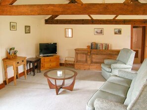 Ein Wohnzimmer mit einer Couch, einem Fernseher, einem Holzschrank und einem Couchtisch.