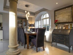 Un comedor con candelabro, ventana amplia y aparador antiguo.