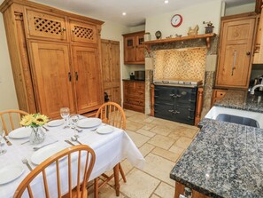 Una cocina con armarios de madera, encimera de granito y una mesa de comedor preparada para cuatro personas.