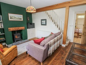 Una sala de estar acogedora con un sofá, una chimenea, una escalera y un comedor.