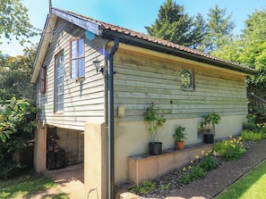 Ein Holzhaus mit schrägem Dach, einem Hauseingang und einer kleinen Veranda mit Blumentöpfen.
