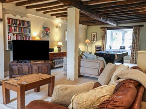 A cozy living room with a sofa, a coffee table, a bookshelf, a television, and a pool table. - The Old Manor House, Lifton (Lifton)