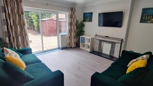 Una sala de estar con sofás verdes, televisor y chimenea.