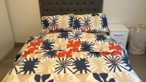Un dormitorio con cama, cabecera, un cuadro en la pared y mesita de noche.