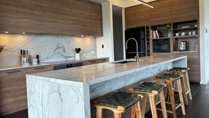 Una cocina moderna con encimera de mármol, armarios de madera y una barra integrada con taburetes.