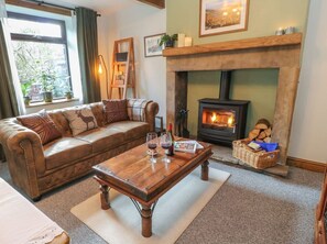 Ein gemütliches Wohnzimmer mit einer Ledersofa, einem Holztisch, einem Kamin und einem Fenster mit Pflanzen.