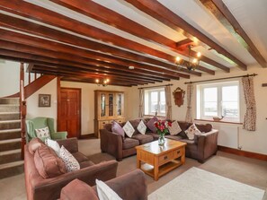 Ein Wohnzimmer mit Treppe, Holzbalken und Kamin.