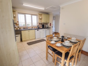 A compact kitchen with a dining area, a dishwasher, and a window with blinds. - Nursery Cottage, Lincolnshire. (Louth)