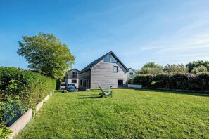 A modern house with a sloped roof, a car parked in the driveway, and a well-maintained lawn. - Sea Haze Retreat in Tenby (Tenby)