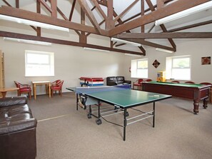 Una habitación con mesa de ping pong, mesa de billar, sofá y mesa de comedor con sillas.