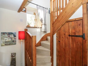 A wooden staircase leading to a room with a window, a red lamp, and a painting on the wall. - 1 Mill Farm Cottages, Narberth (Narberth)