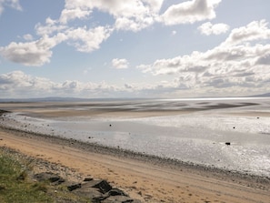 A beach with a clear sky and distant mountains.