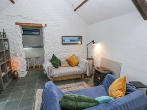 Ein gemütliches Schlafzimmer im Loft-Stil mit Bett, Sofa, Kamin und einer durch einen Bogen sichtbaren Küchenzeile.
