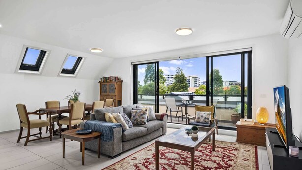 A modern living room with a sofa, coffee table, and dining area. - Comfortable 2 Bed Stay with Parking (Footscray)