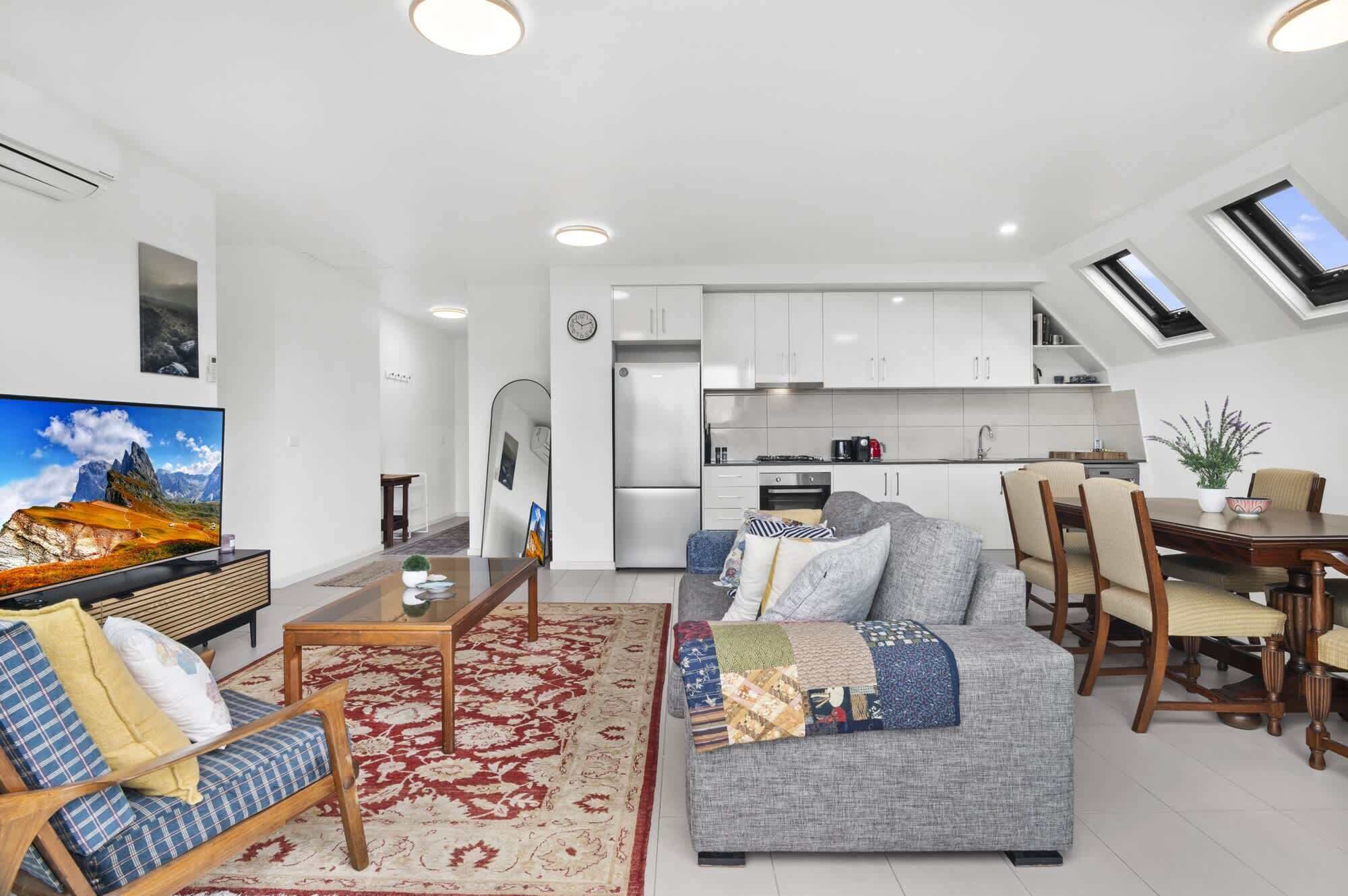 A modern apartment with a living room, dining area, kitchen, and a balcony with a view.