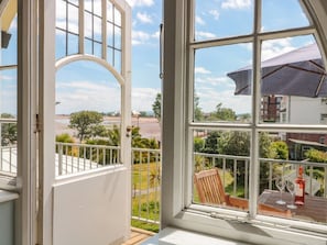 Ein Zimmer mit großem Fenster, einem Holzstuhl und einem Tisch mit zwei Weingläsern und einer Flasche.