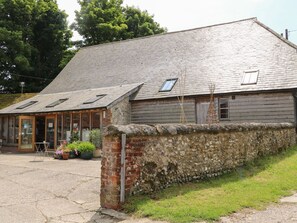 A rustic building with a sloped roof, a stone wall, and a glass door entrance. - Byre Cottage 3 (2 bed), Storrington (Pulborough)